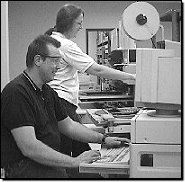 Ellen Yango and Bert Maslowski operate automatic insertion equipment.